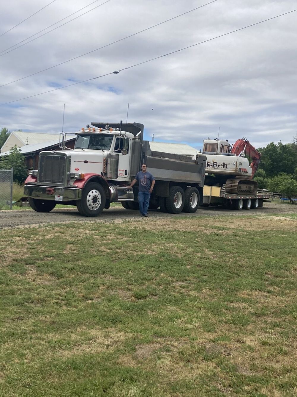 Russco Enterprises owner standing beside the company's 10-yard dump truck and excavator in Douglas County, Oregon.